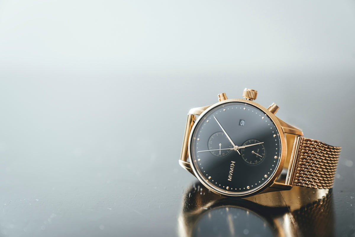 round gold-colored and black MVMTH chronograph watch with link bracelet