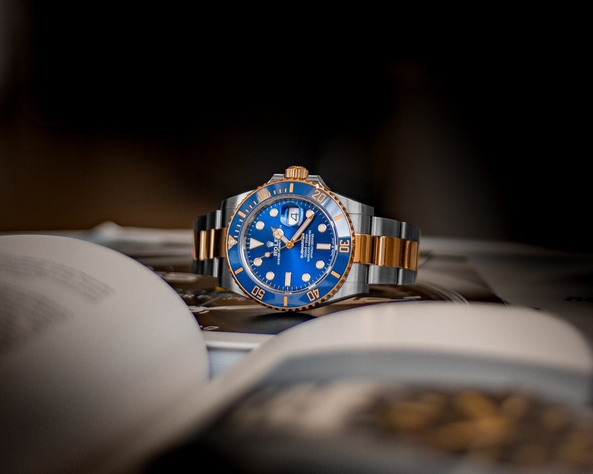 A blue and gold luxury wristwatch resting on an open book