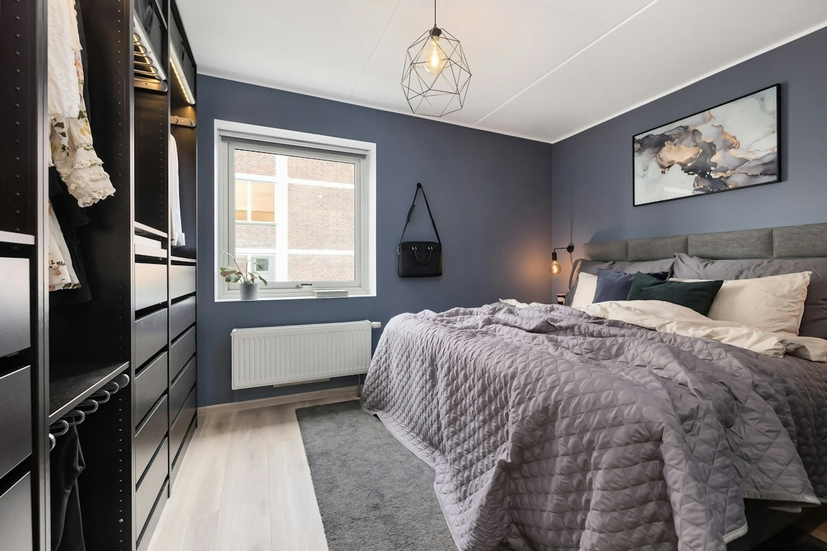 A bed room with a neatly made bed and a dresser