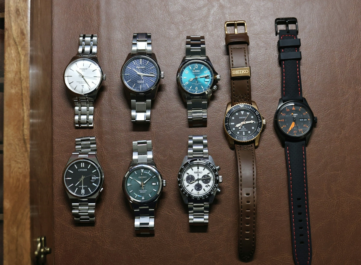 Collection of assorted wristwatches on a brown surface